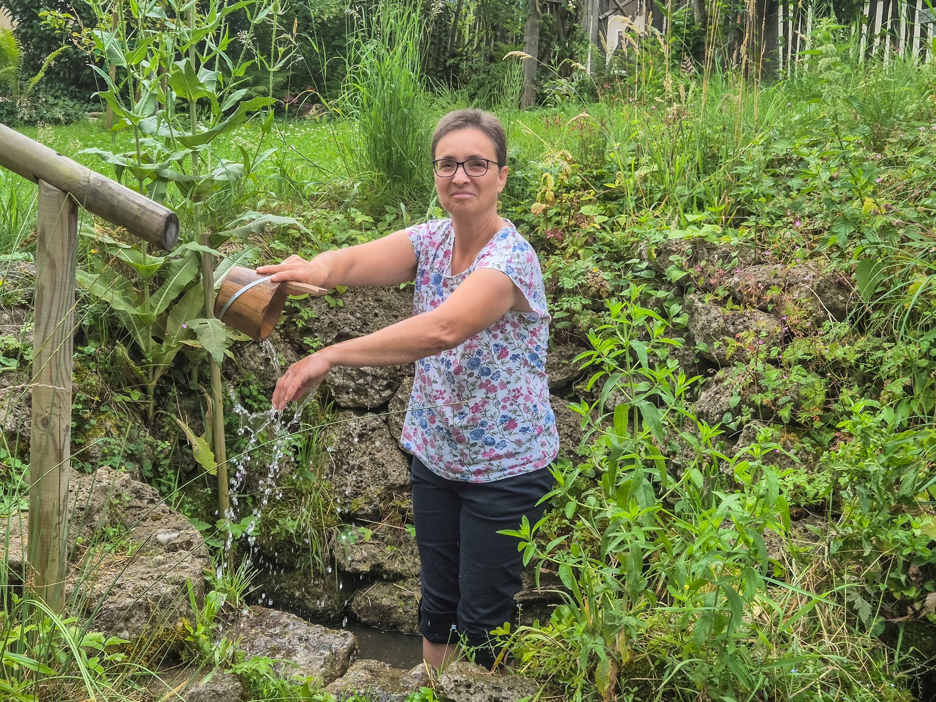 Barbara Spindler übergießt ihre Arme mit dem Wasser vom Gesundheitsgartl Teisendorf