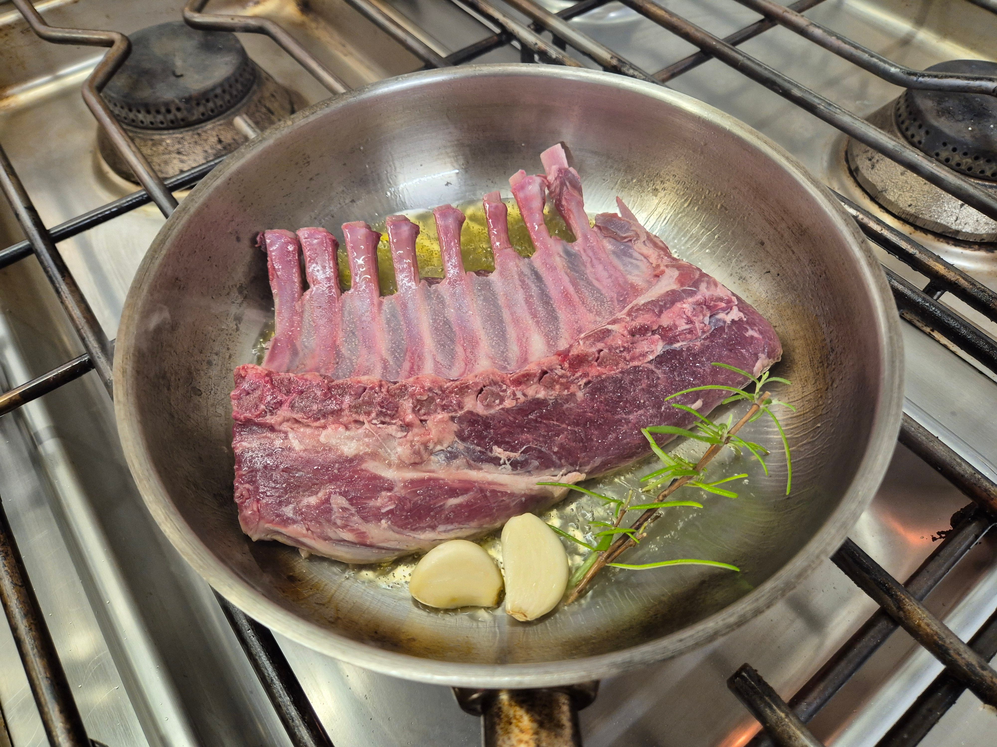 Lammrücken wird Rosmarin und Knoblauch in der Pfanne angebraten