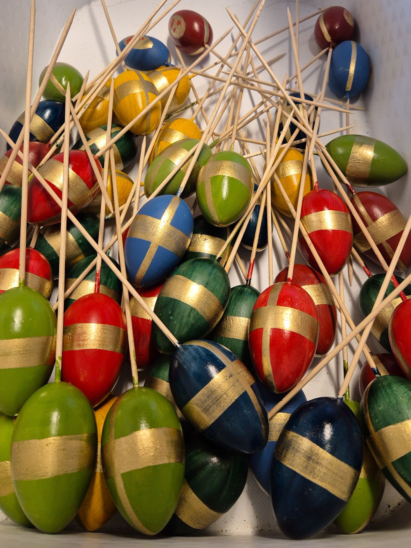 Eier in den Grundfarben vor der Verzierung in grün, rot, blau mit goldenen Streifen