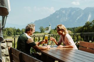 Ein Paar genießt Essen und Aussicht auf der Terrasse der Neubichler Alm