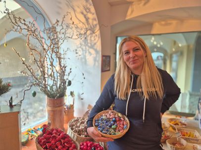 Astrid von der Handwerkskunst hält im Laden einen Korb fertig verzierter Ostereier