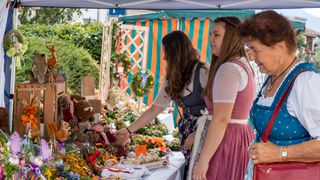 Drei Damen im Dirndl vor einem Verkaufsstand am Rupertimarkt Piding
