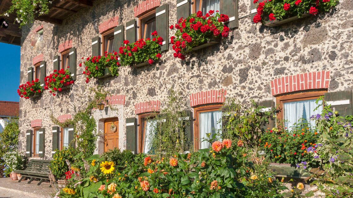 Bauernhaus aus Schlackestein in Teisendorf mit zahlreichen Blumen an der Fassade