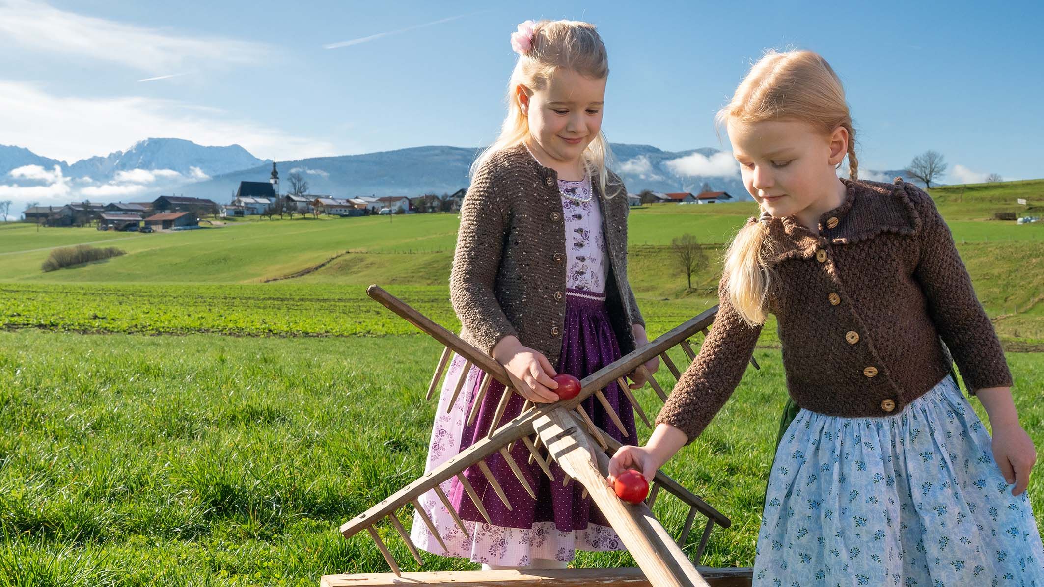 Kinder lassen die Ostereier über die Rechen runterrollen